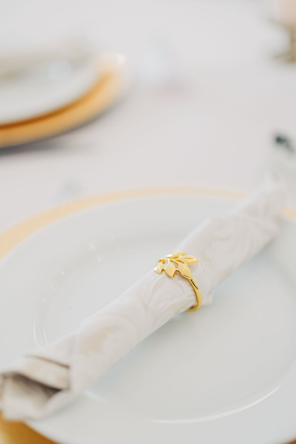White linen napkins with gold utensils arranged in an elegant table setting.