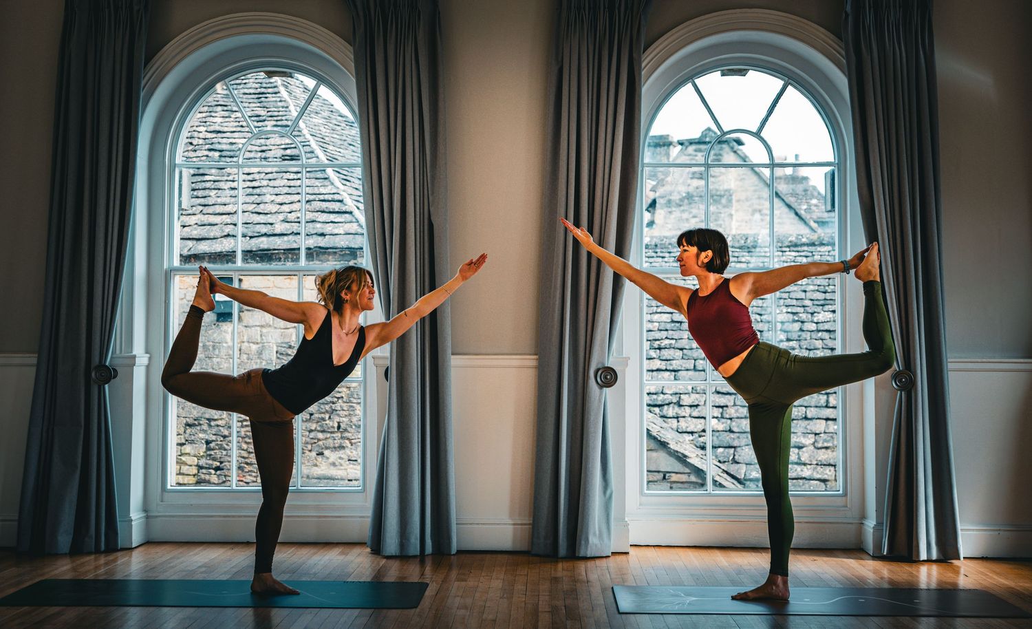 A series of dance poses showing graceful leg extensions and stretches in front of an arched window in a studio.
