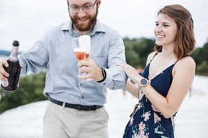 People holding coffee cups and beverages while walking and smiling outdoors on a sunny day.