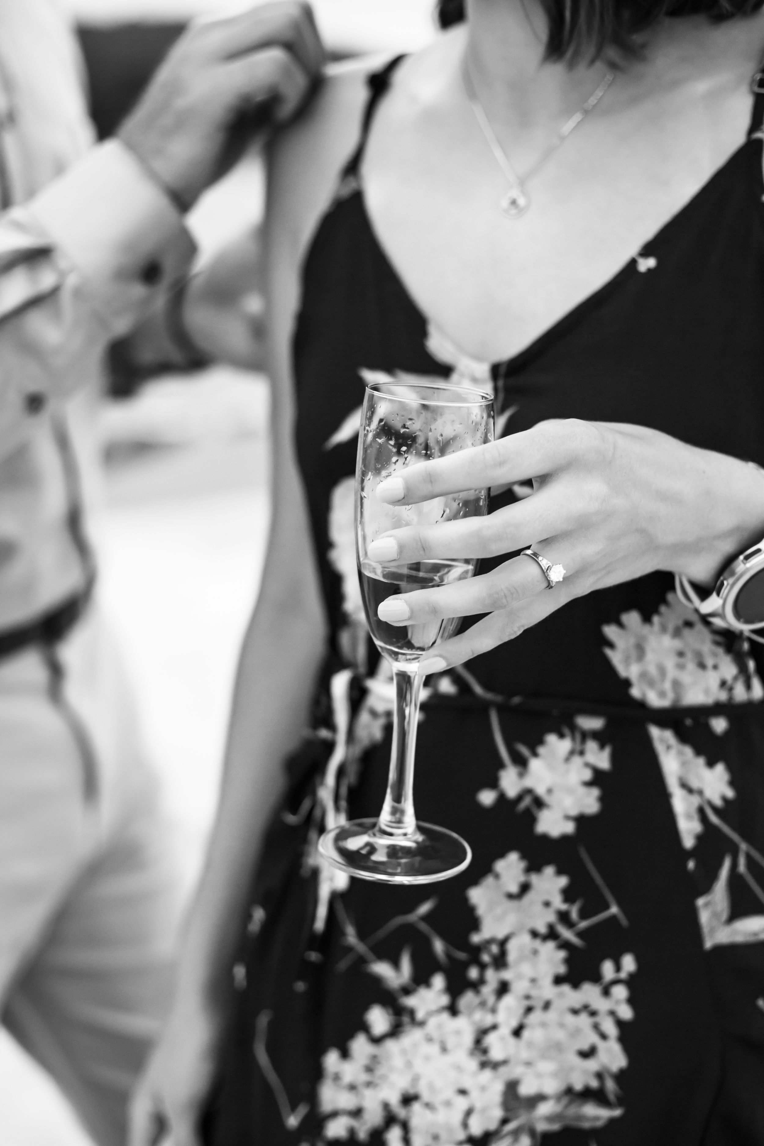 Close-up black and white shots of champagne glasses being held during a celebration.