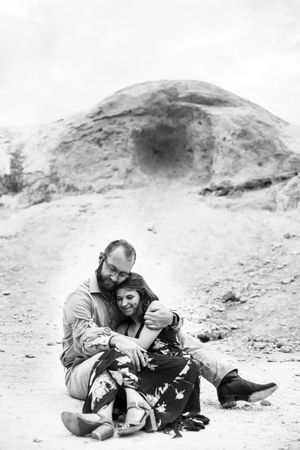 Black and white photo of a couple laying together on white rocks.