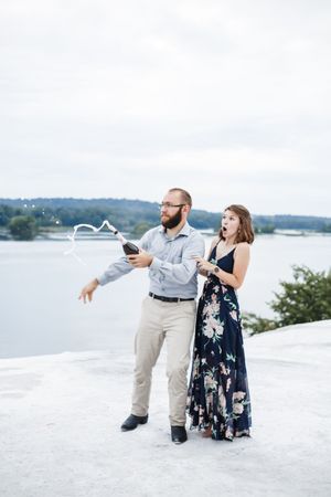 Couple in navy dress and khakis share joyful moments on bright white rocks by the lake.