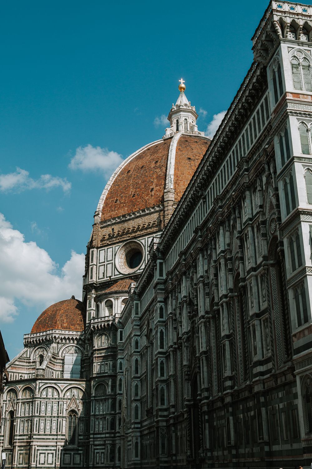 Die imposante Kuppel und verzierte Fassade der Kathedrale von Florenz (Duomo) unter strahlend blauem Himmel in Italien.
