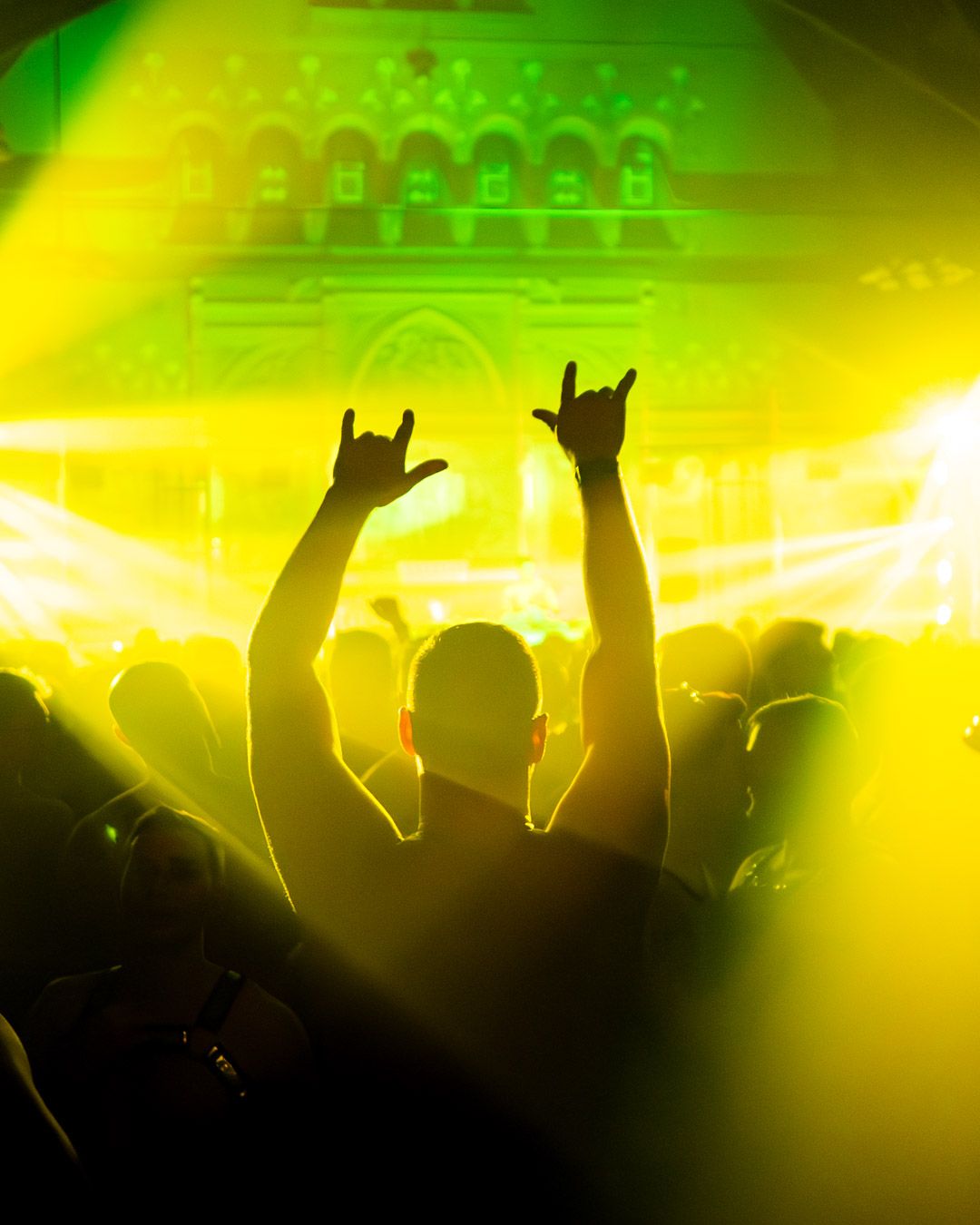 A partygoer at a nightlife event hosted by Dusty Carpenter raises his hands while dancing