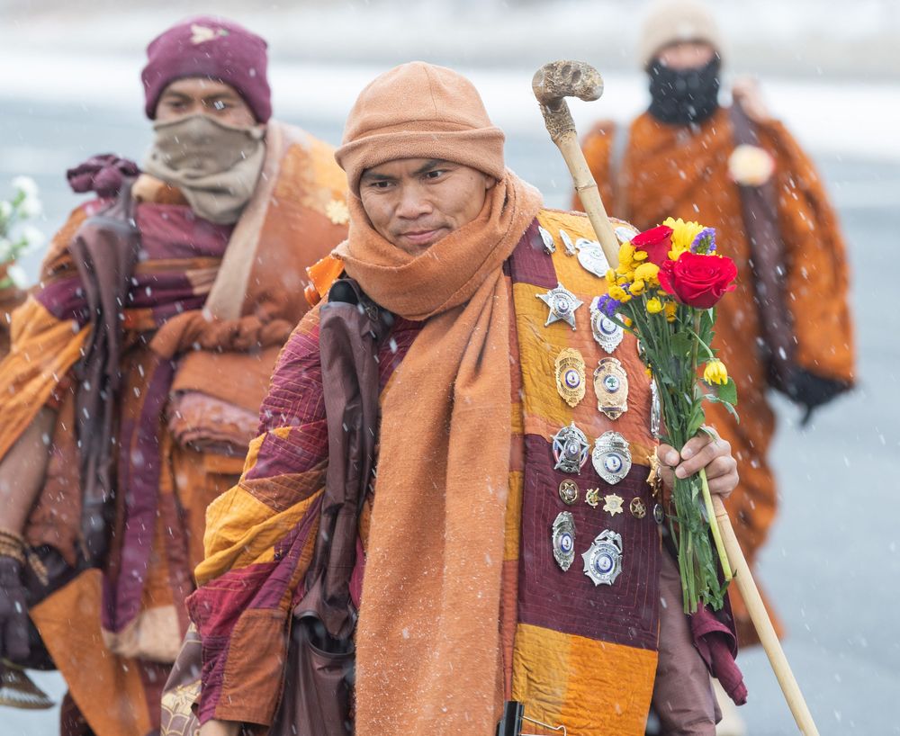 Buddhist monks in traditional orange and burgundy robes gather during a religious ceremony in a temple courtyard.