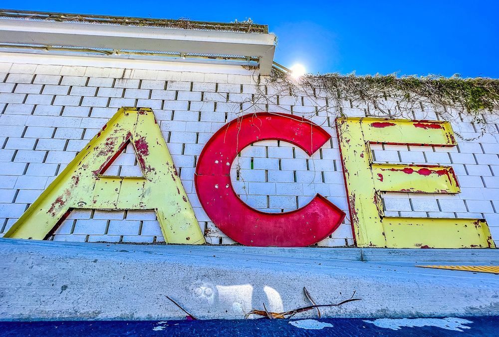 A panoramic view of colorful graffiti art on a long wall against a bright blue sky.