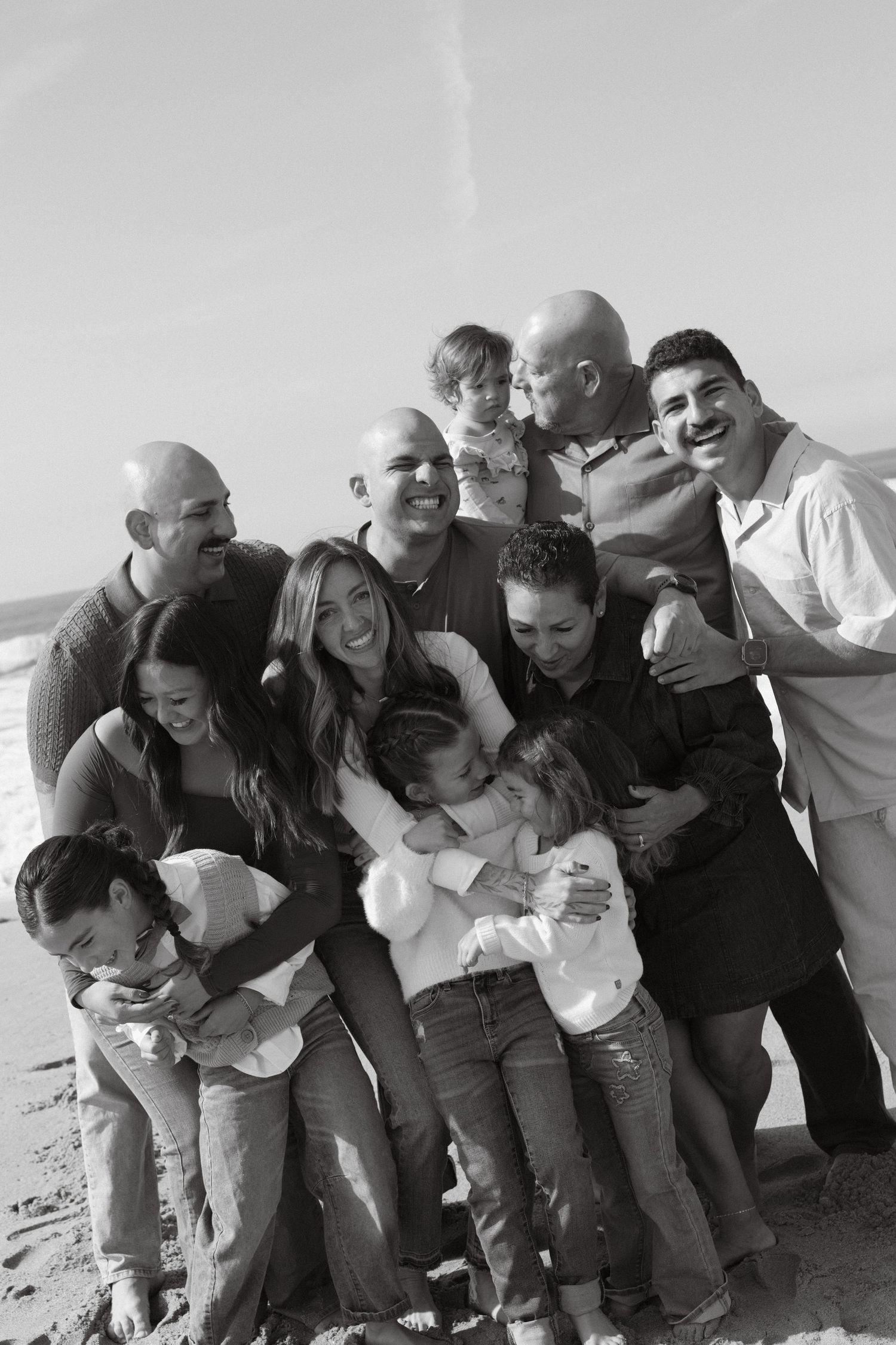 Black and white extended family photo in Ventura, California with everyone hugging and laughing together