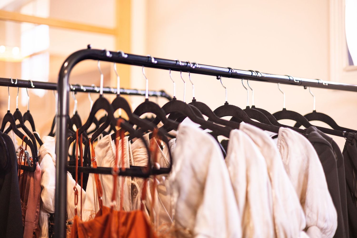 Rows of white and black clothing hanging neatly on retail display racks in a clothing store. Bradenton Florida Branding Photographer
