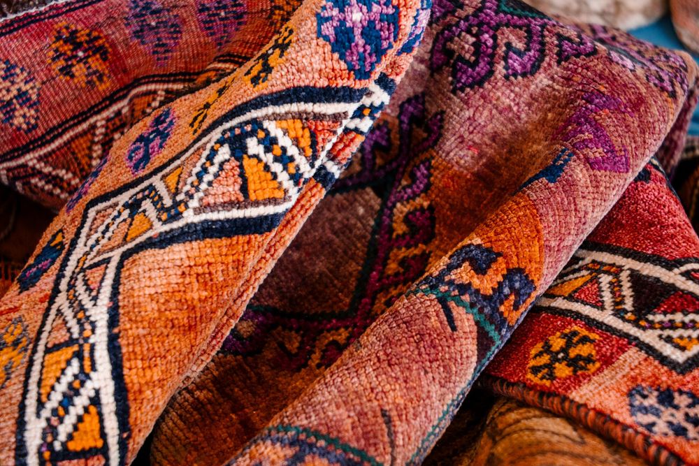 Colorful traditional handwoven Persian rugs with intricate geometric patterns in rich red, orange, and blue tones.