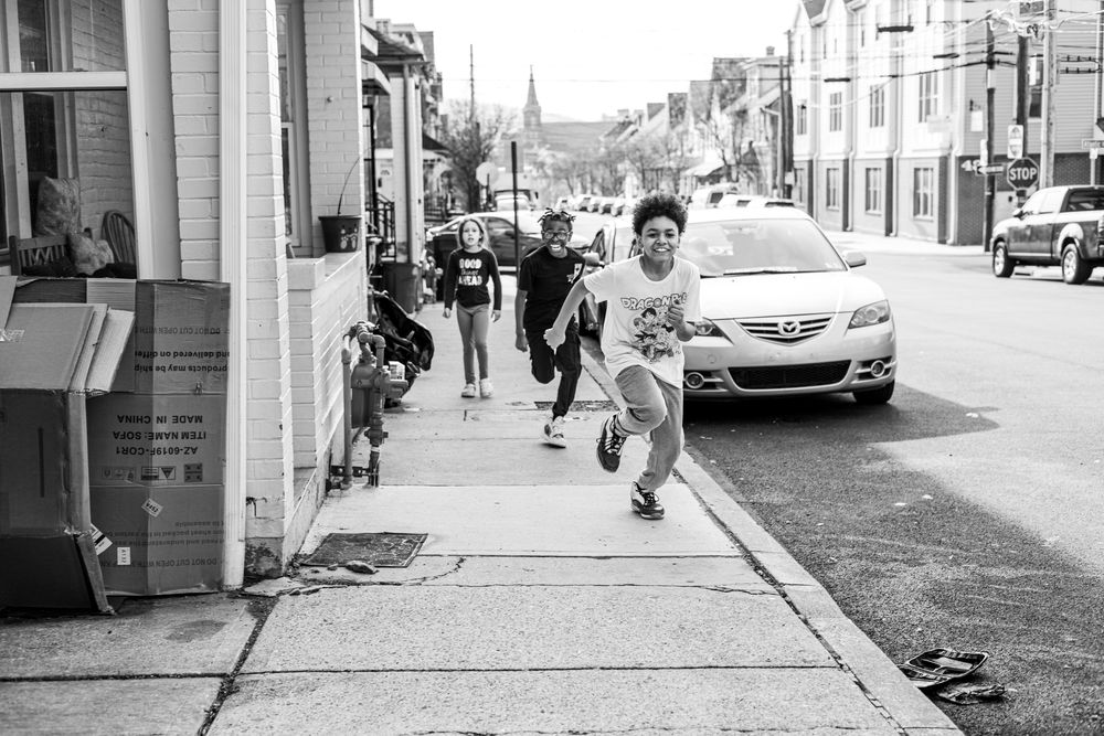 Young person running energetically along a city sidewalk in black and white street photography.