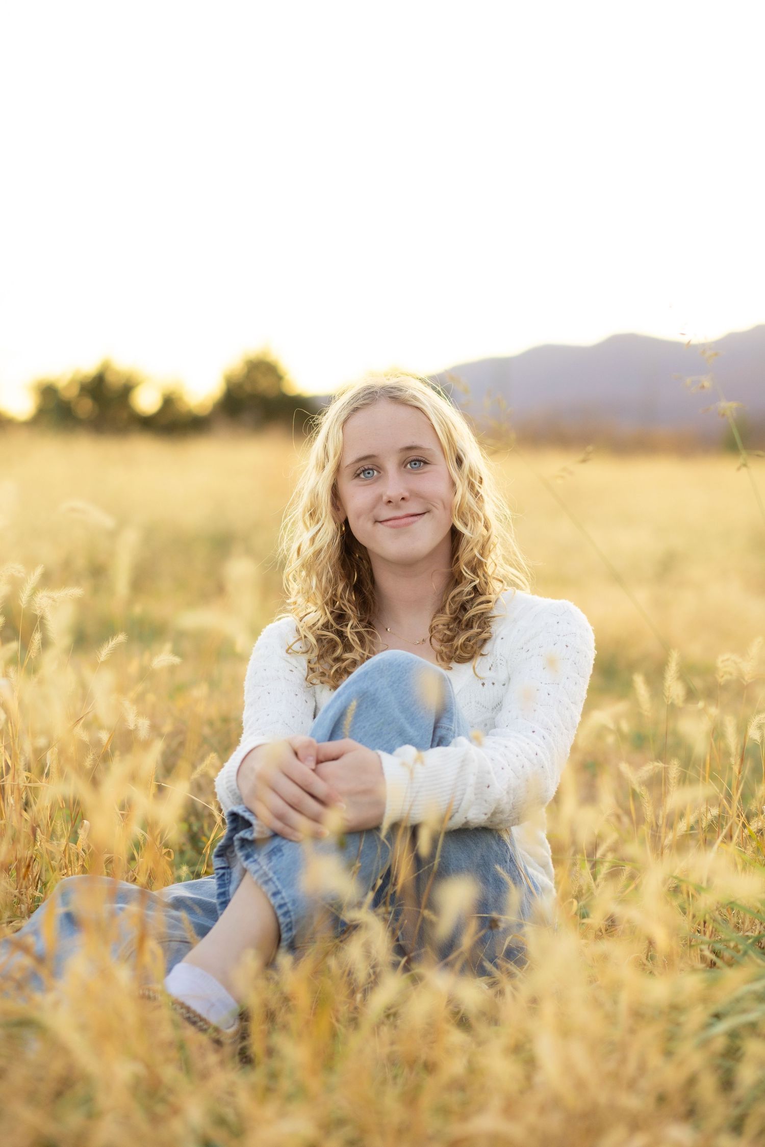 A series of four golden hour portraits in a sun-drenched field with tall grass and warm lighting.