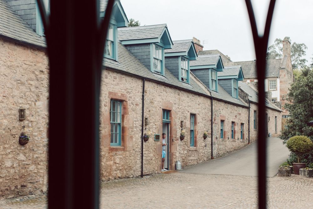 Row of historic stone cottages with dormer windows and blue painted doors along a residential street.