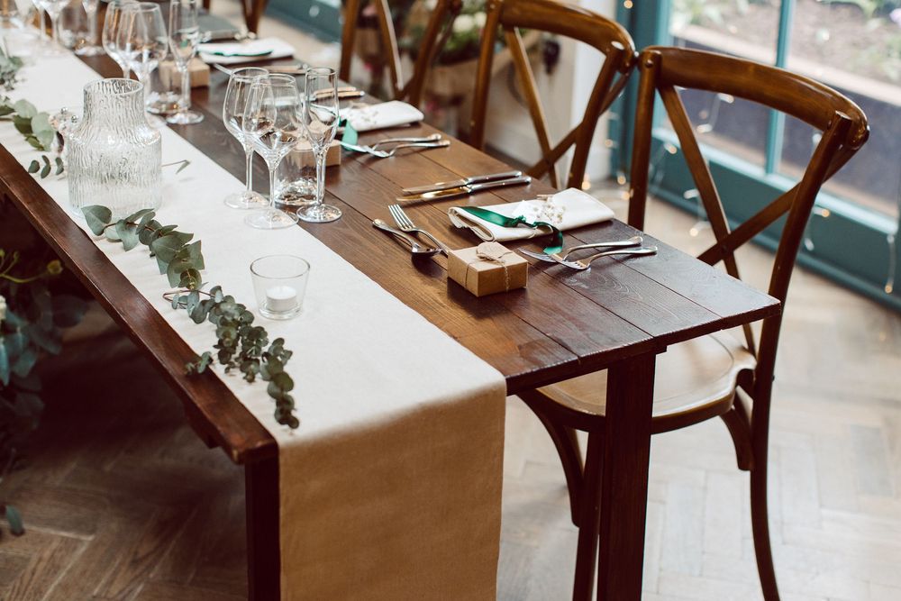 A wooden chair sits at a rustic table in a sunlit restaurant interior with warm, cozy ambiance.