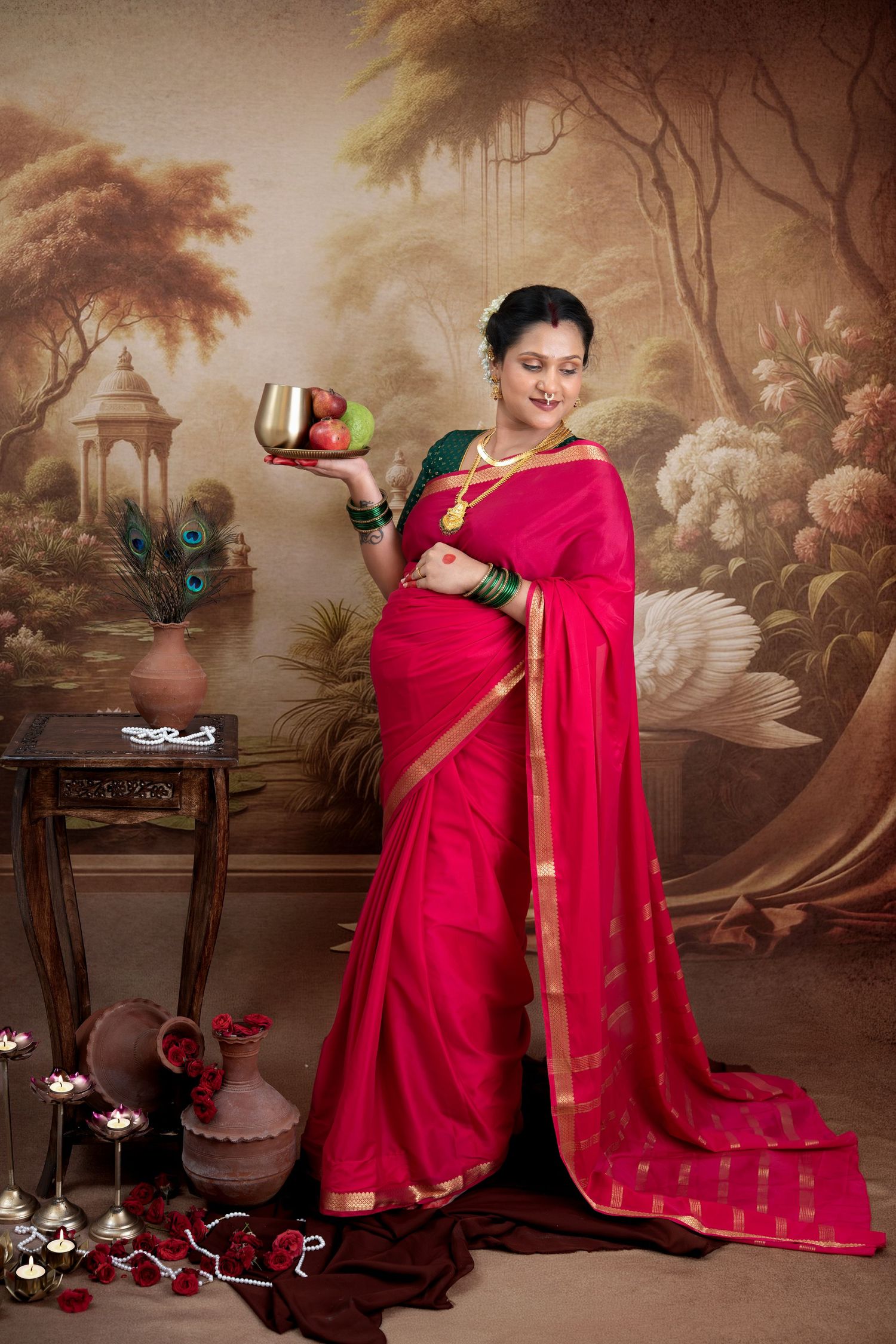 Traditional maternity photoshoot in Hyderabad with mother in red saree, cultural setup and elegant studio backdrop