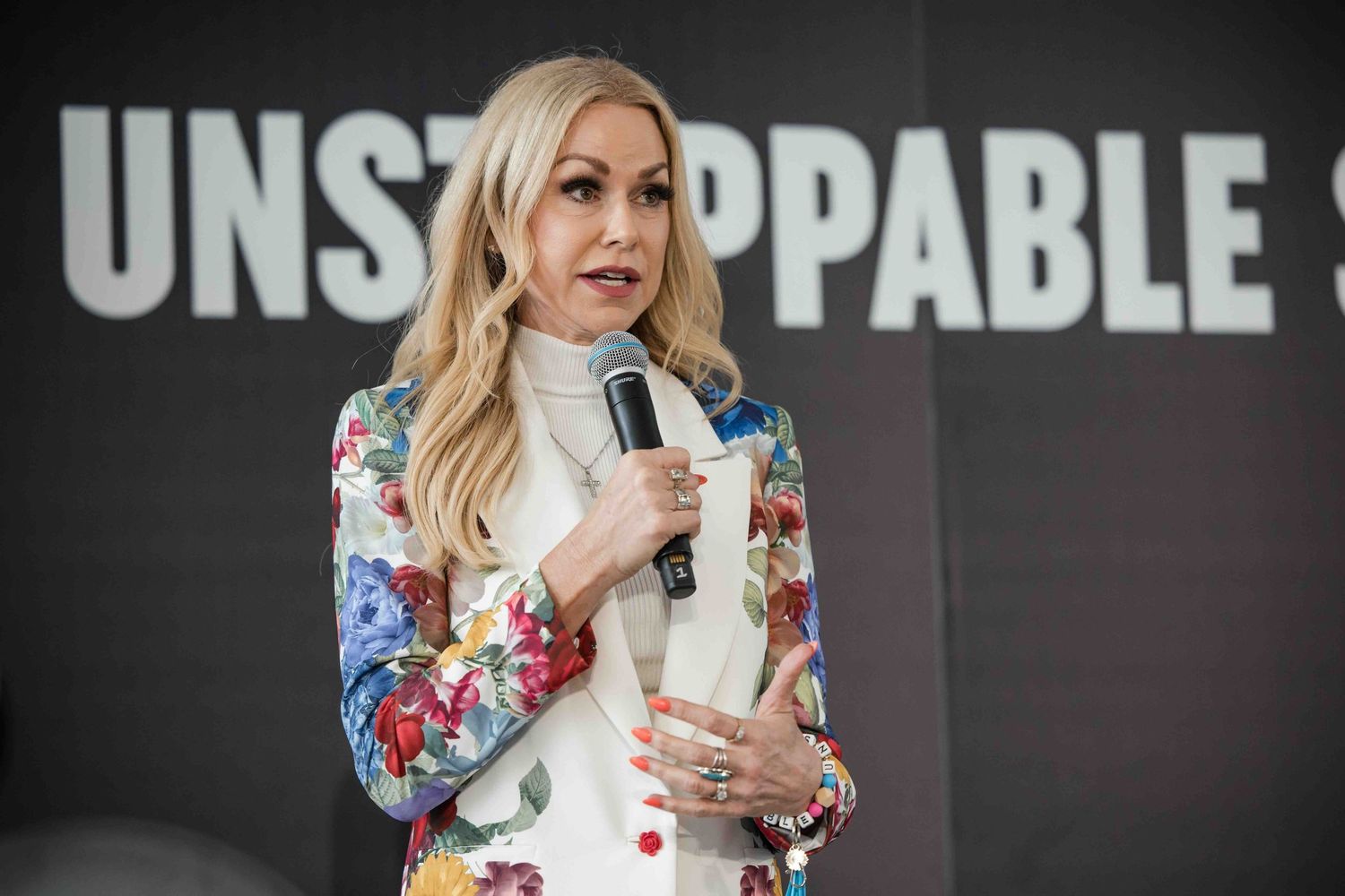The host of Unstoppable 2025 Amberly Lago talking on stage in front of her event logo in a promotional video