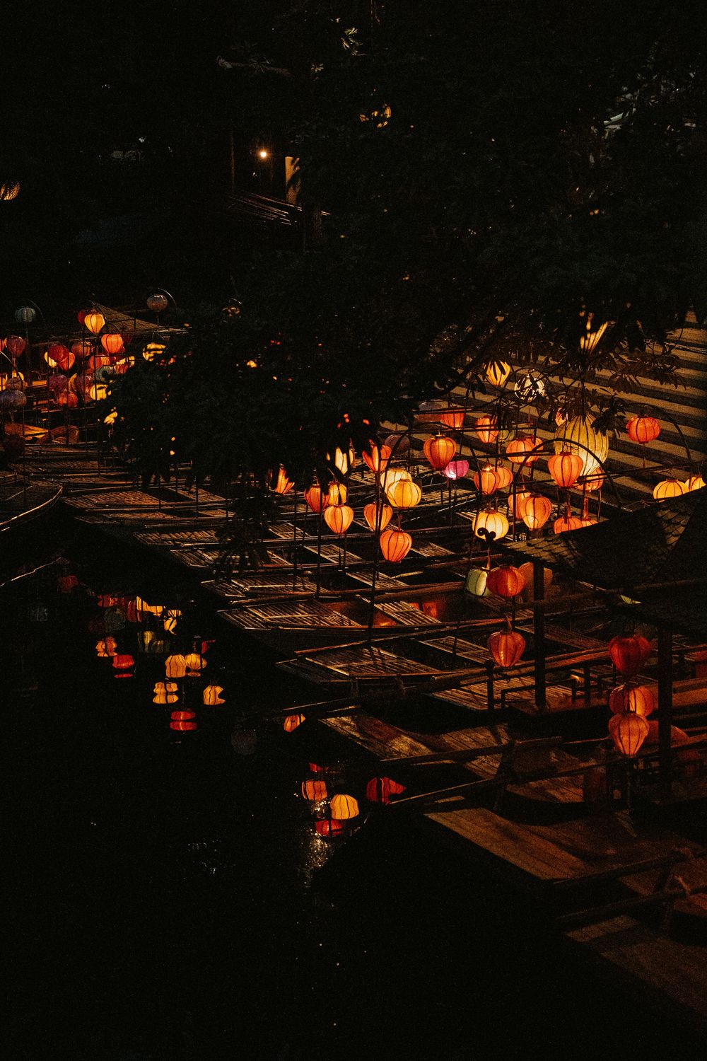 Des lanternes lumineuses colorées se reflètent sur l'eau la nuit à Hoi An, au Vietnam, créant une atmosphère de fête magique.