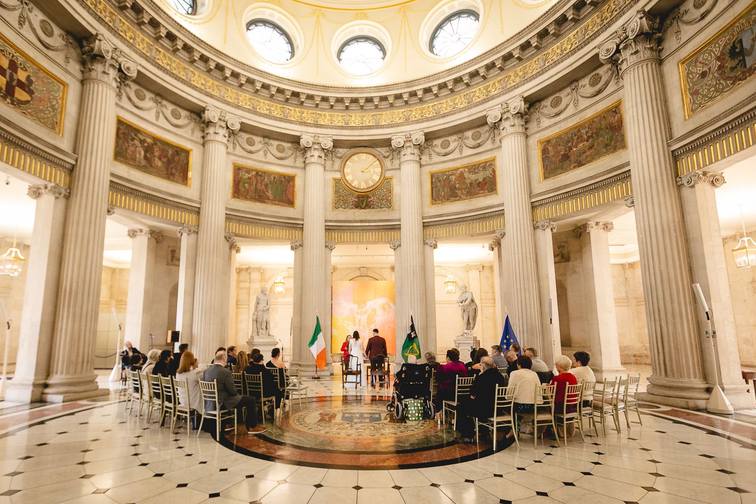 Wedding ceremony in ornate rotunda with guests seated around couple at Dublin City Hall.