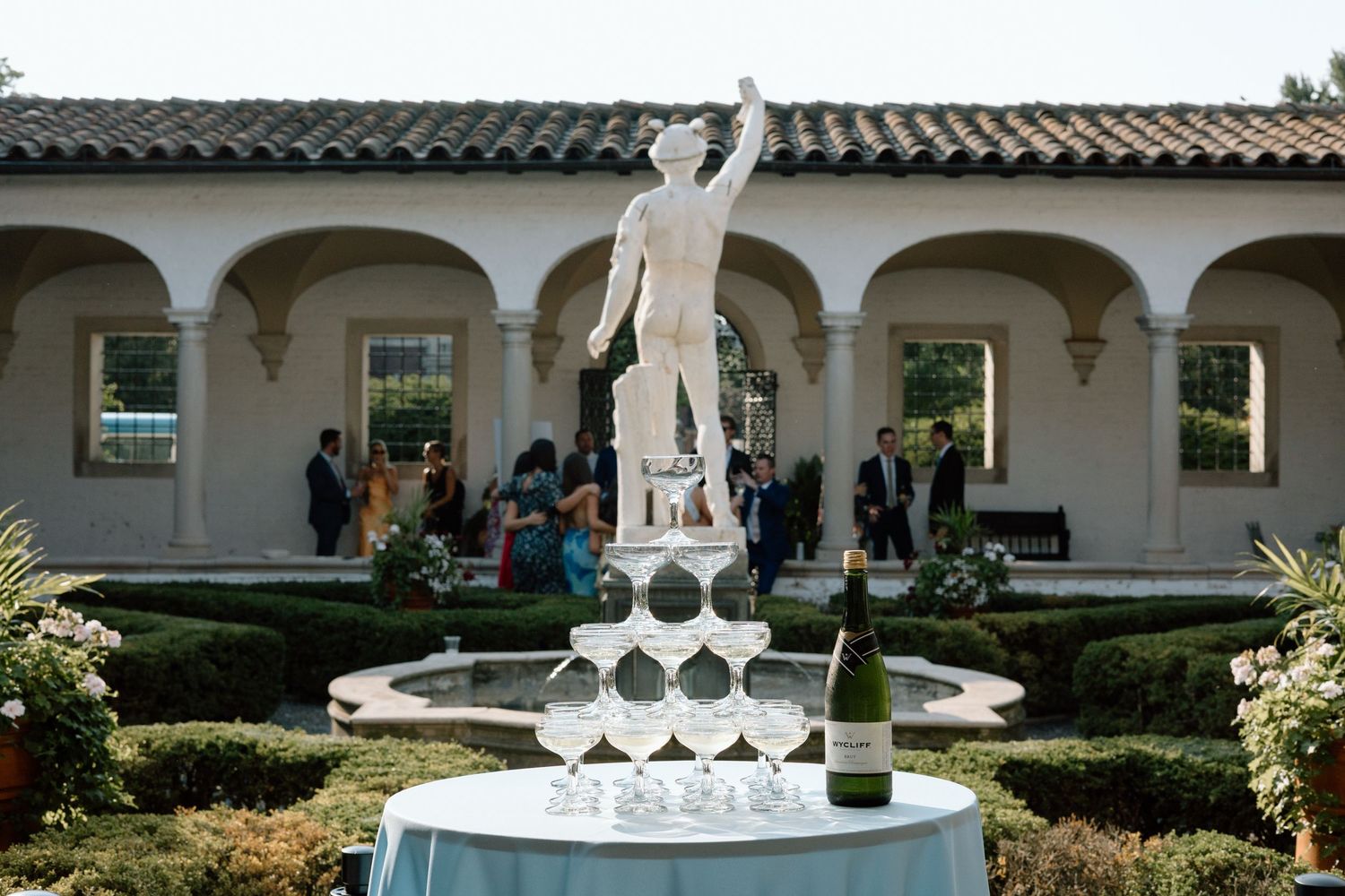 Editorial cocktail hour at The Villa Terrace with champagne fountain beside a classical statue captured by Ashton Gonnering Photography