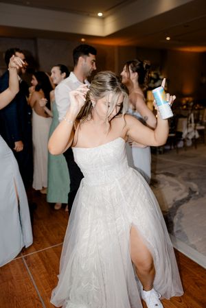 Dancers enjoying a celebration on a wooden dance floor at a formal event in a dimly lit ballroom.