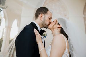 Intimate wedding portrait in front of white architectural details with natural lighting.