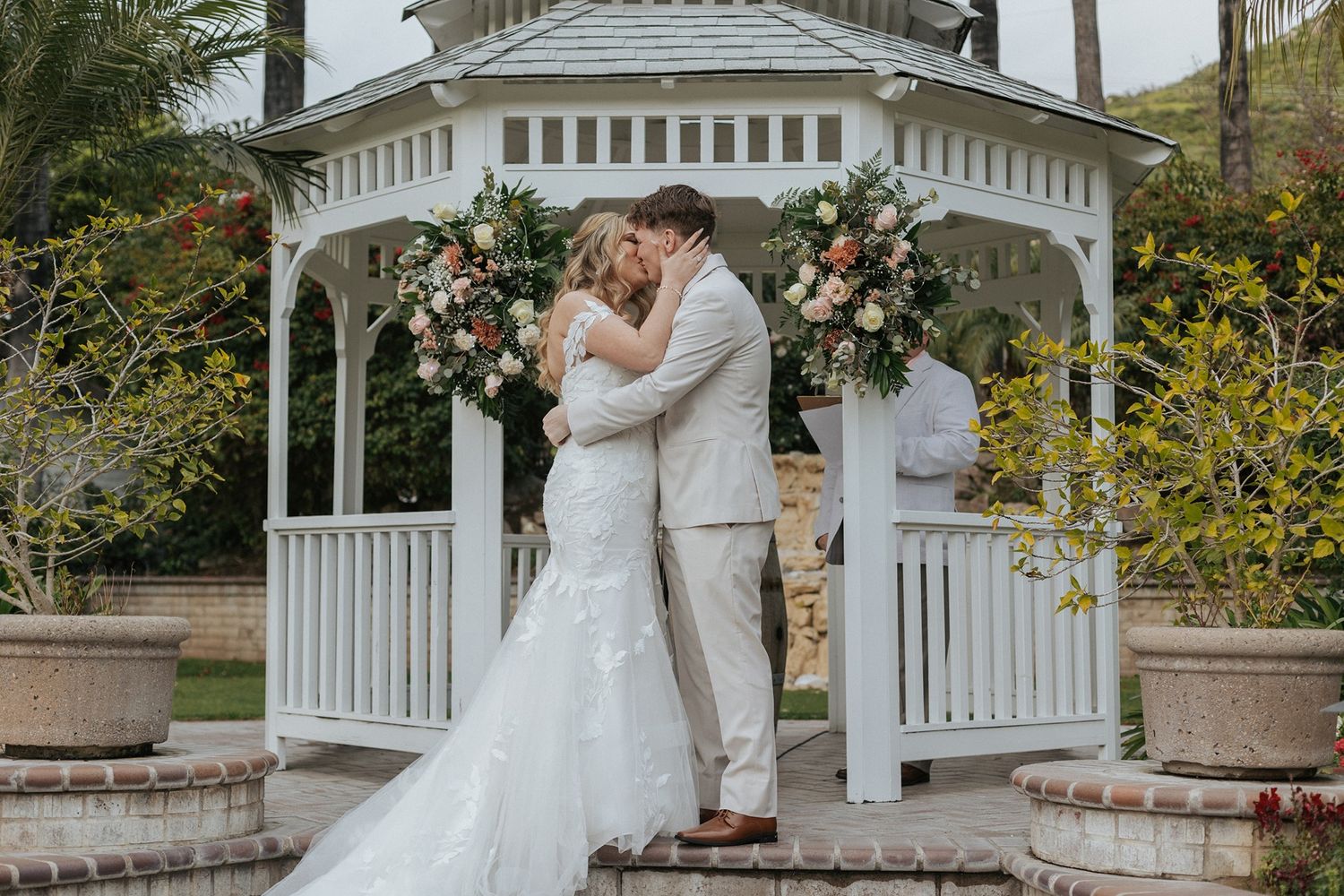 A couple shares a romantic moment under a white gazebo during their wedding ceremony at Singing Hills Golf Resort.