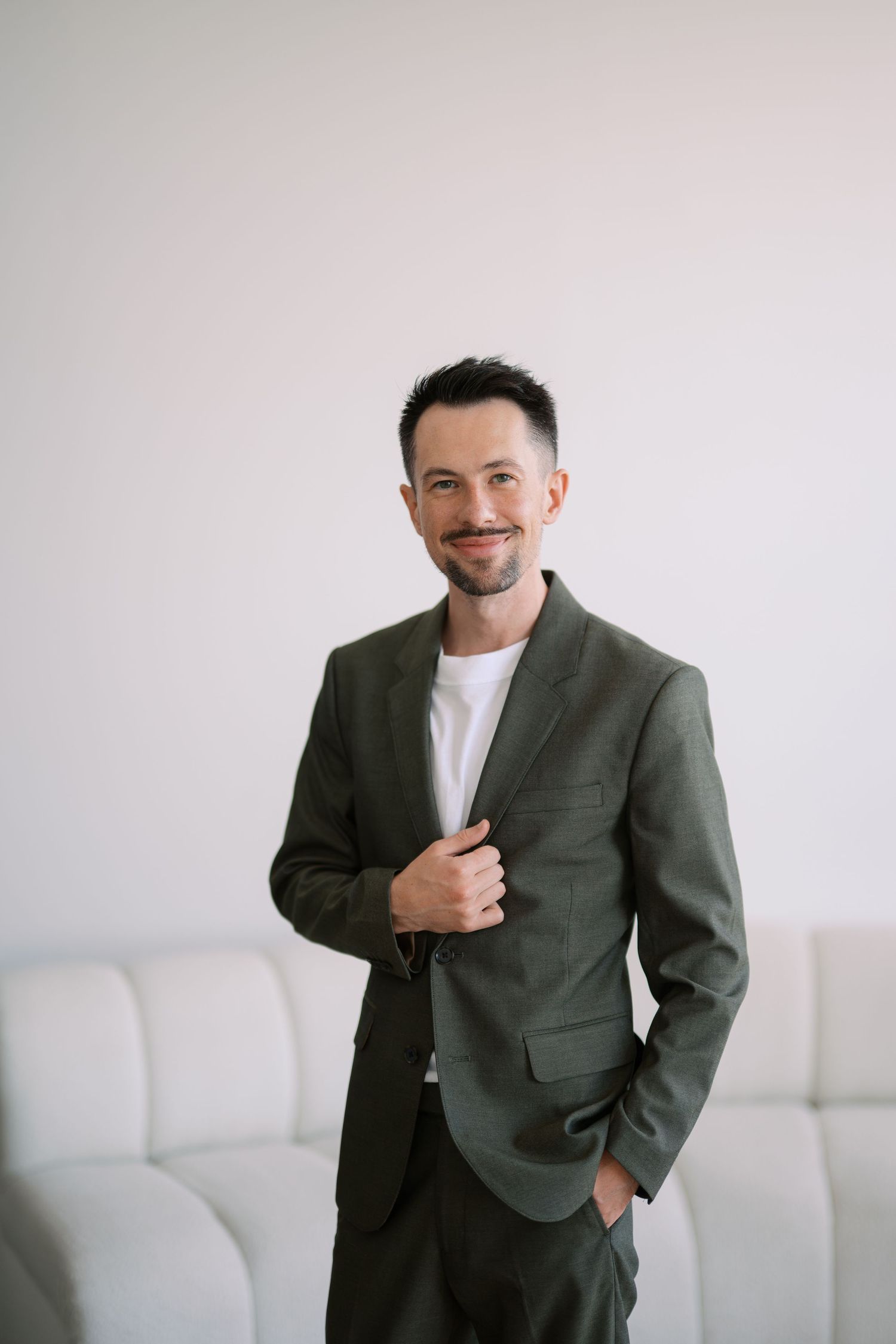 A person in a gray suit and white shirt poses against a white background in a series of four professional headshots.