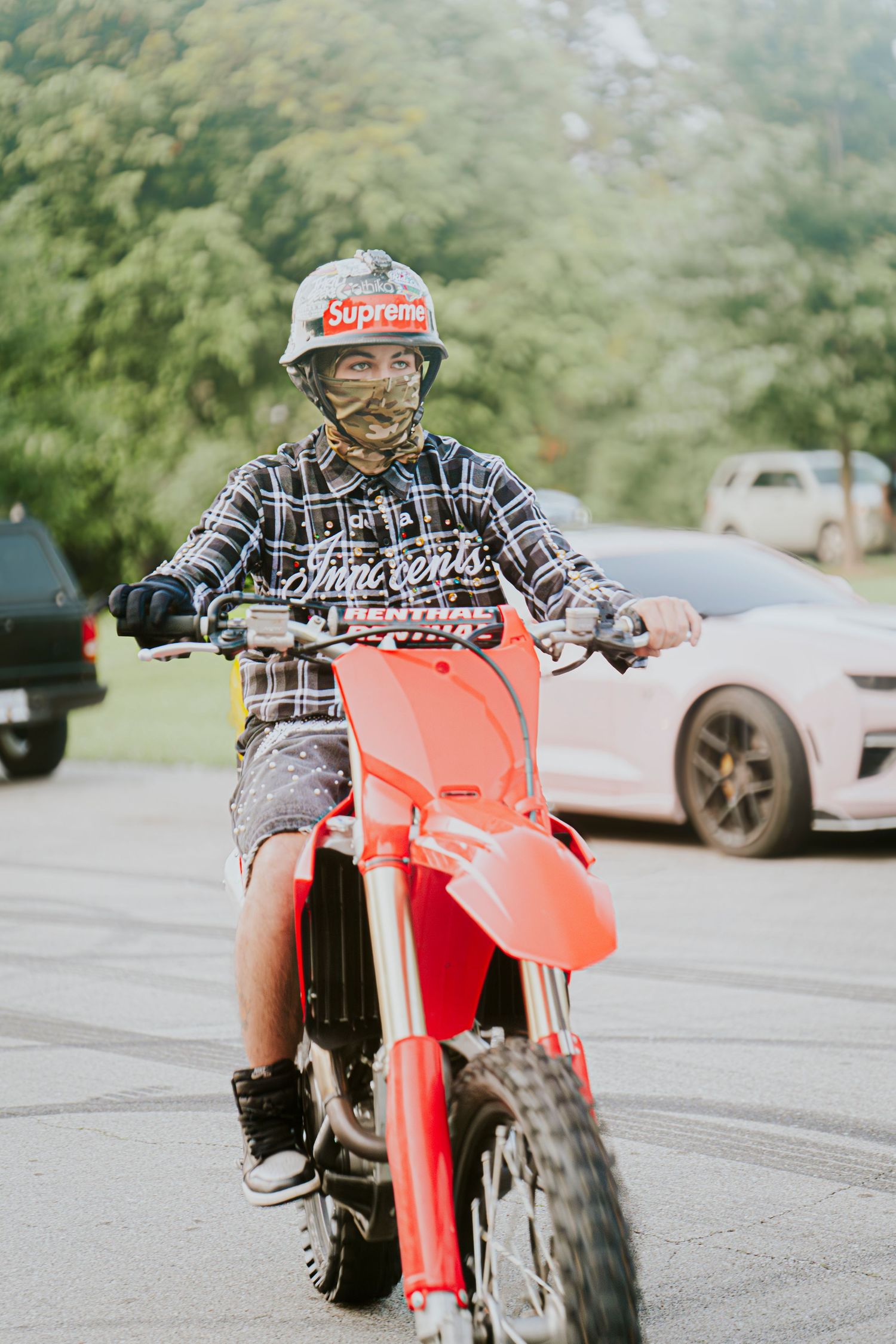 Person riding bright red dirt bike in outdoor parking area.
