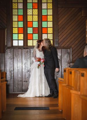 Newlyweds share a romantic kiss at the altar of a rustic wooden chapel.