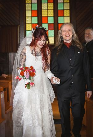 Beaming newlyweds walk down chapel aisle hand in hand after wedding ceremony.