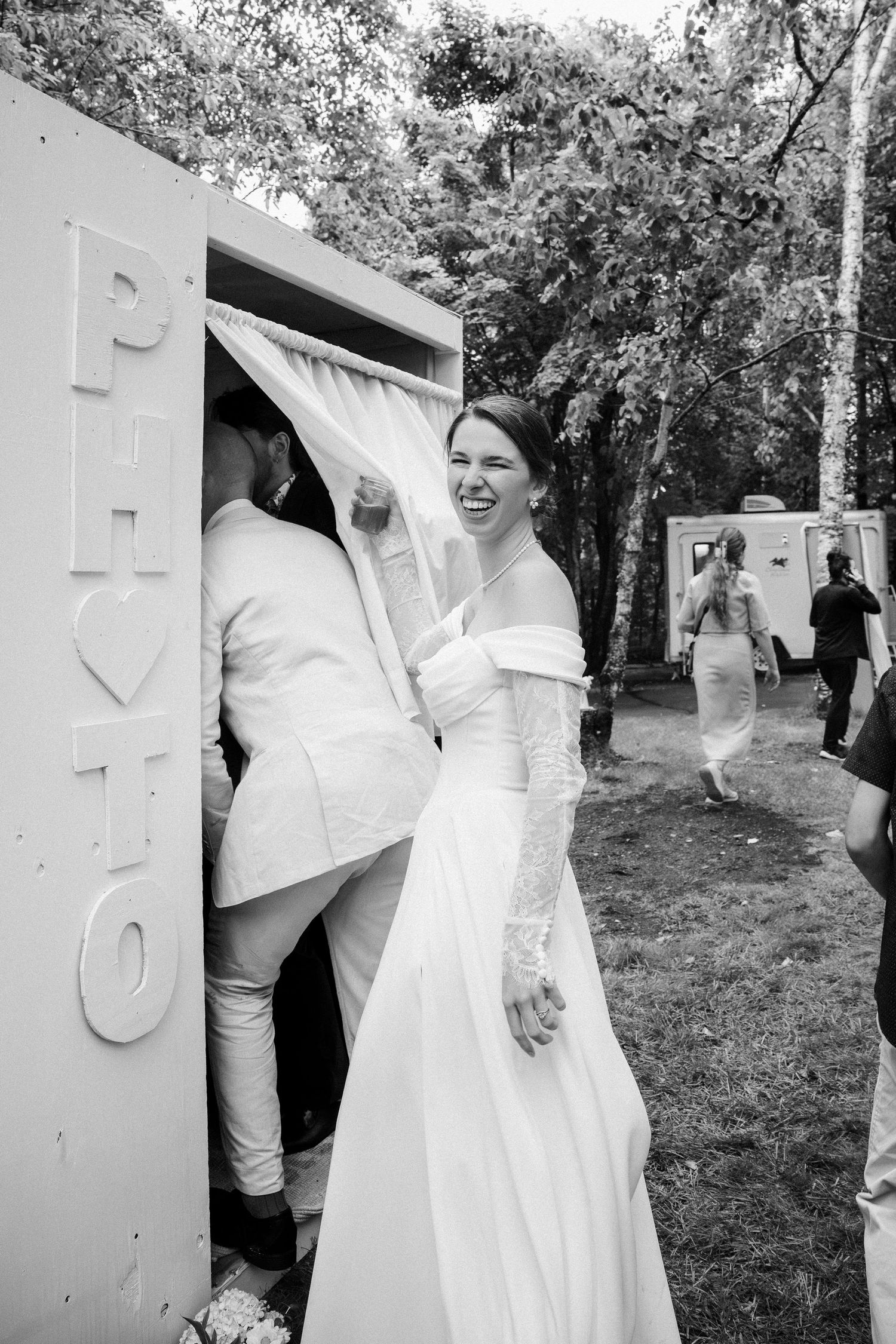 Black and white wedding photo series showing candid moments between a couple in white attire outdoors.