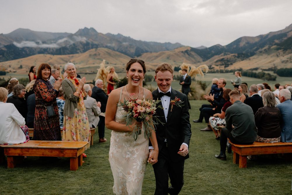 Wedding ceremony setup in a scenic mountain valley with wooden benches and floral arrangements at Lookout Lodge Wanaka, New Zealand.