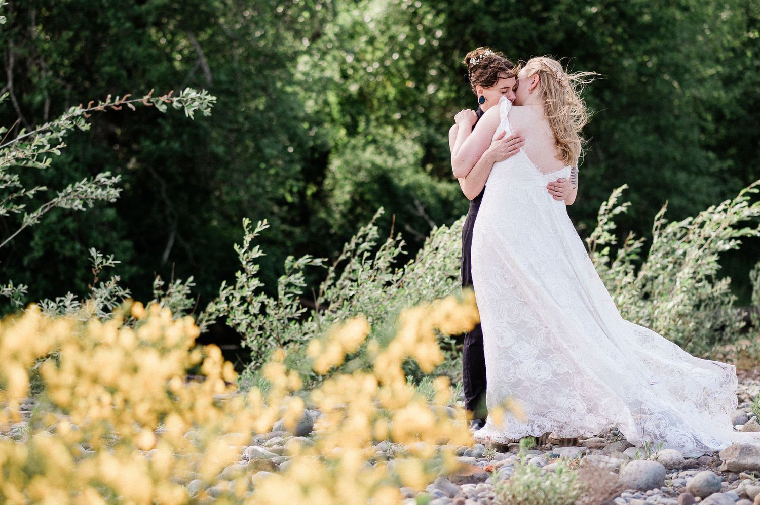 A romantic wedding couple embraces with yellow wildflowers and lush greenery