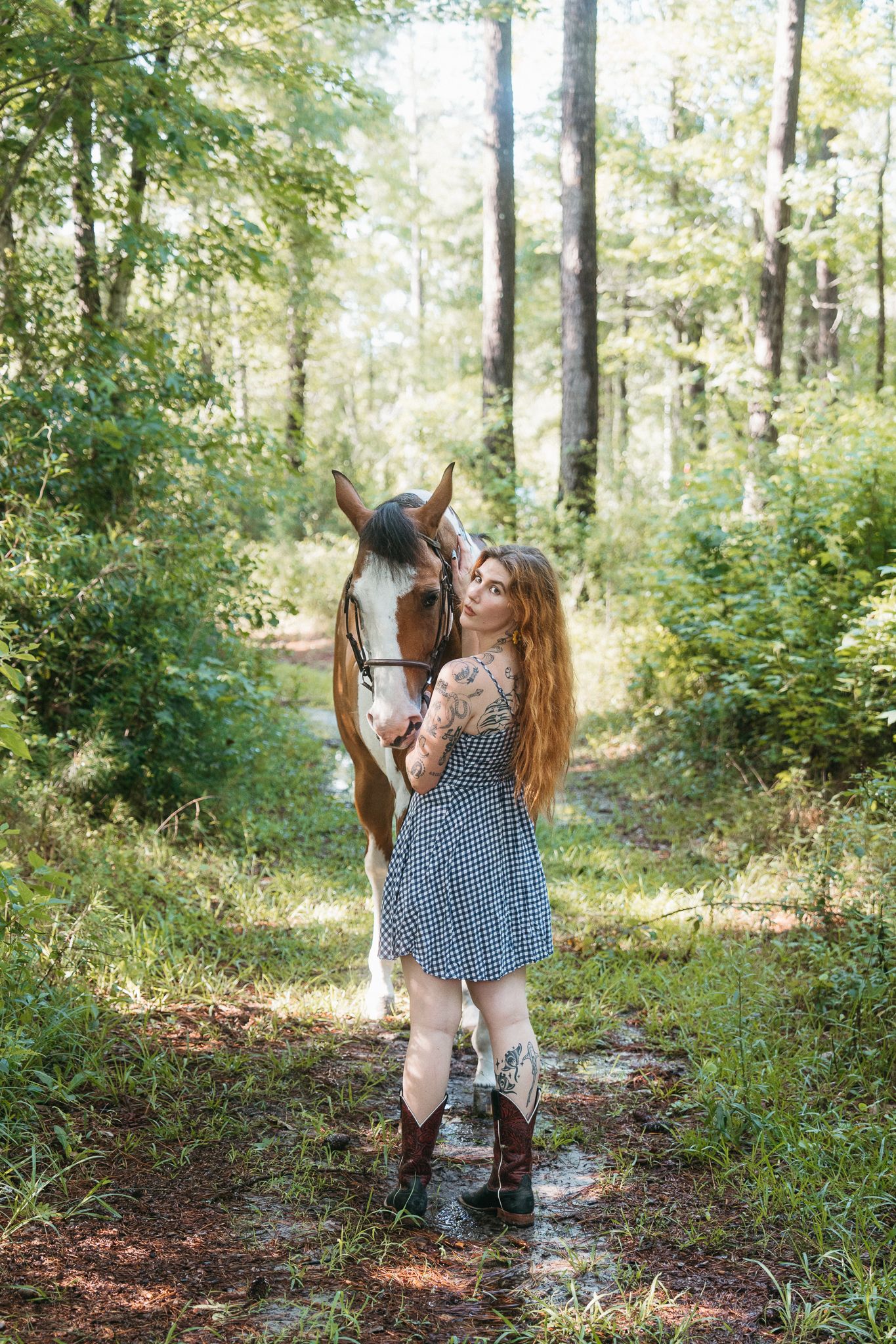 A paint horse and rider enjoy a peaceful moment together on a sunlit forest trail.