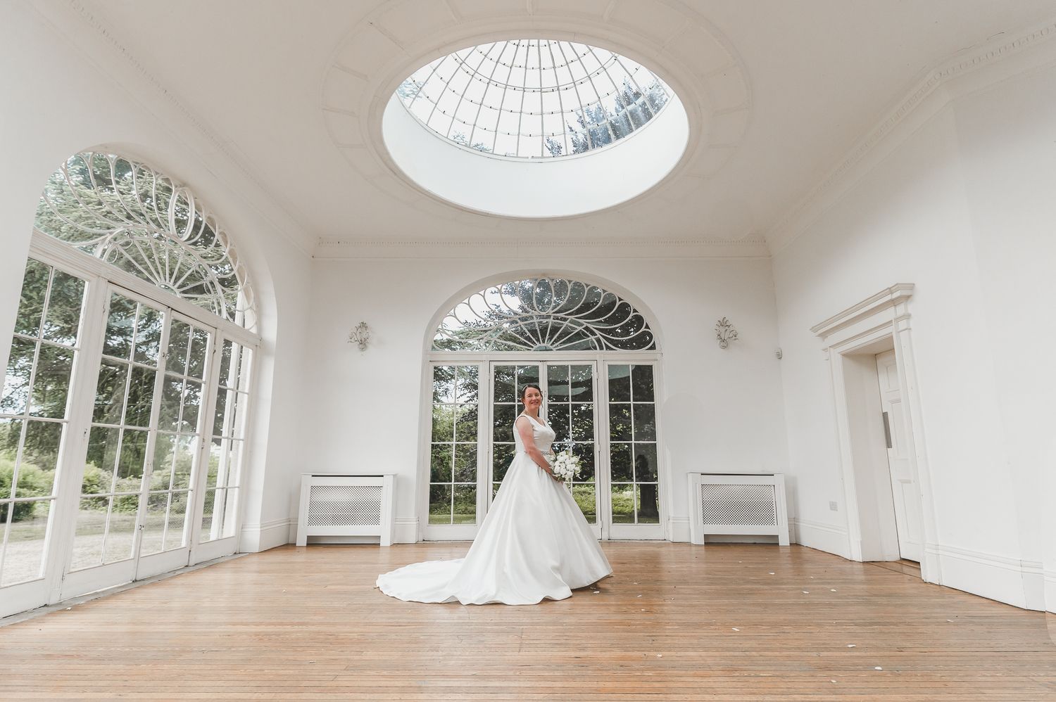 Elegant white conservatory room with glass dome ceiling, hardwood floors and natural light streaming in.