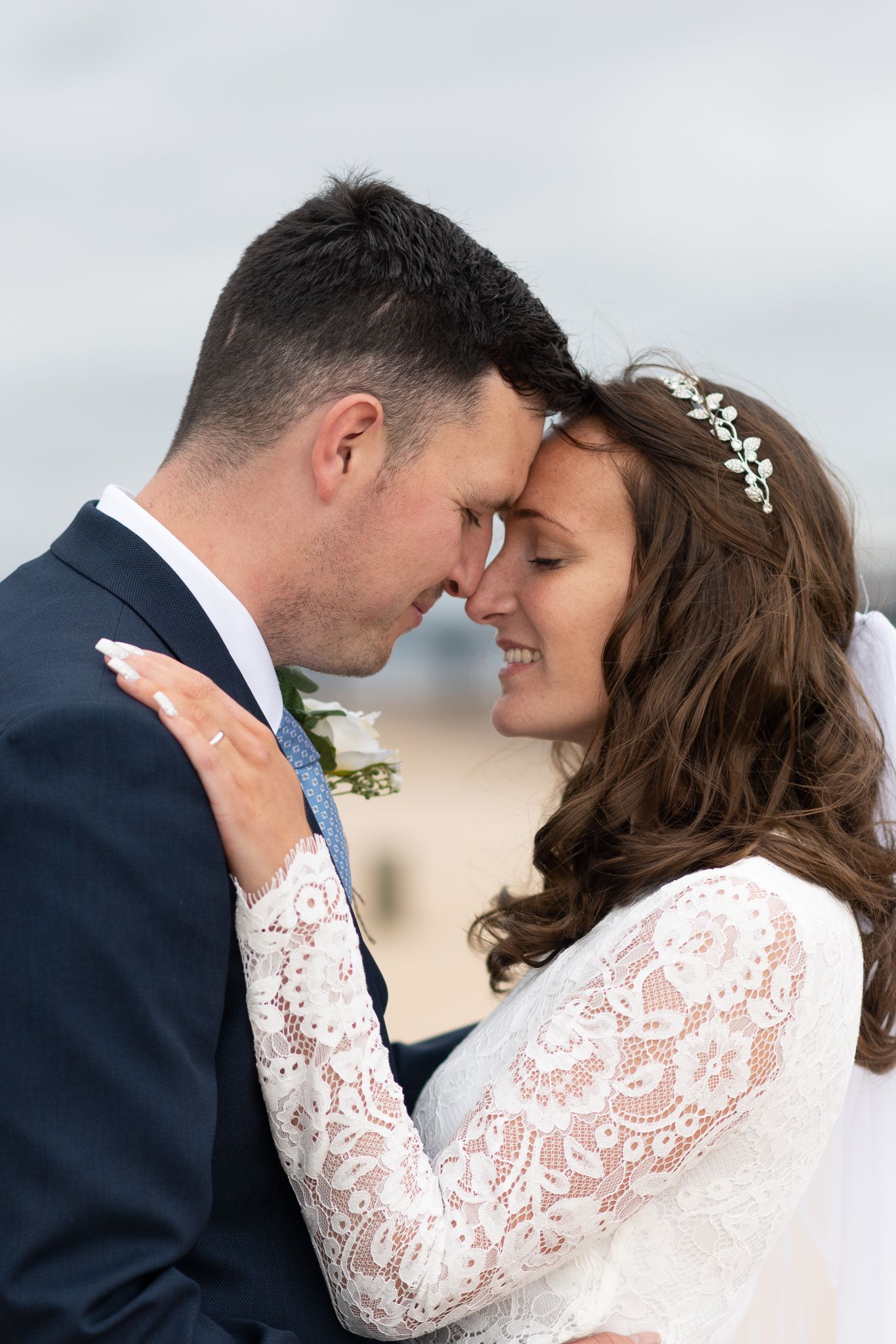 Romantic wedding couple in navy suit and white lace dress share intimate moments in series of tender poses.