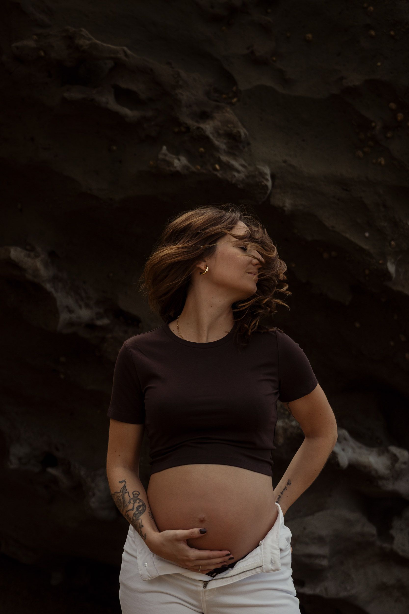 Artistic maternity photo showing a pregnant belly in dramatic lighting.