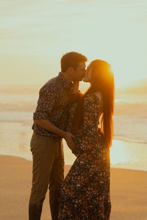 A romantic silhouette of a couple sharing an intimate moment on the beach at sunset.