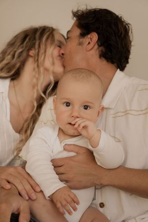 A tender family moment captured in soft, neutral tones against a light background.