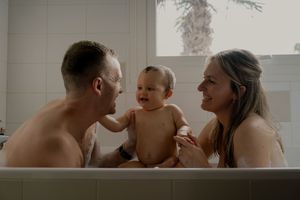 Family sharing an intimate bathing moment with their baby.