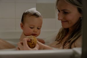 Intimate bath time moment between parent and baby.
