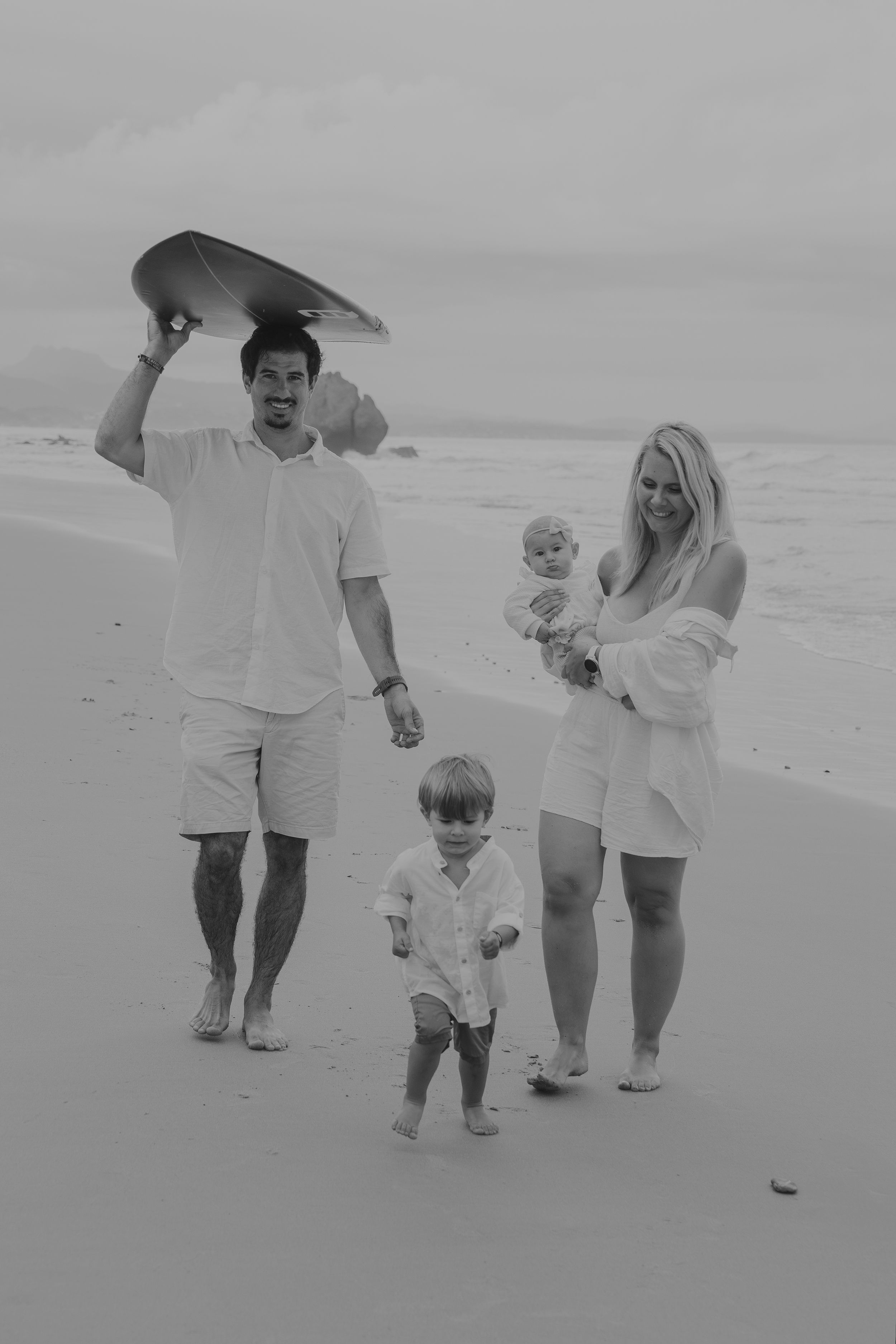 Black and white beach scene with people walking together along the shoreline.