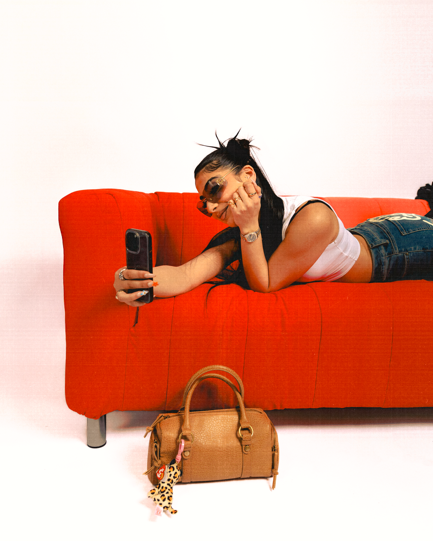 Someone lounges on a bright red couch with a brown leather handbag visible in the scene.