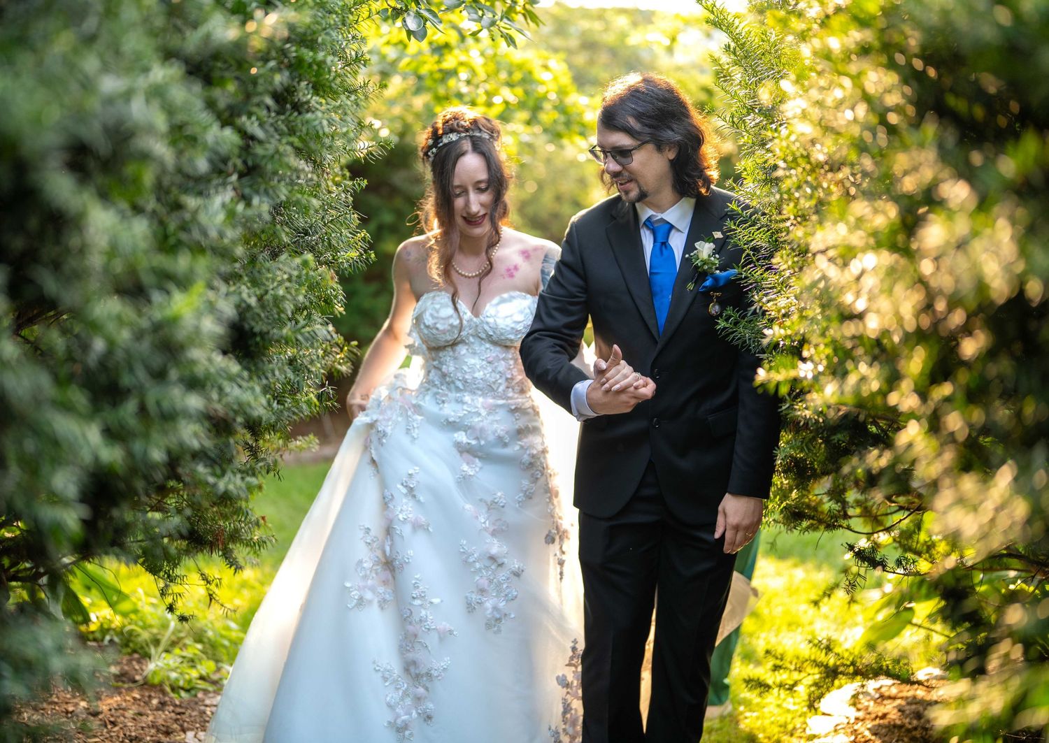 Bride and groom walk through green garden in Toledo Zoo Wedding Venue