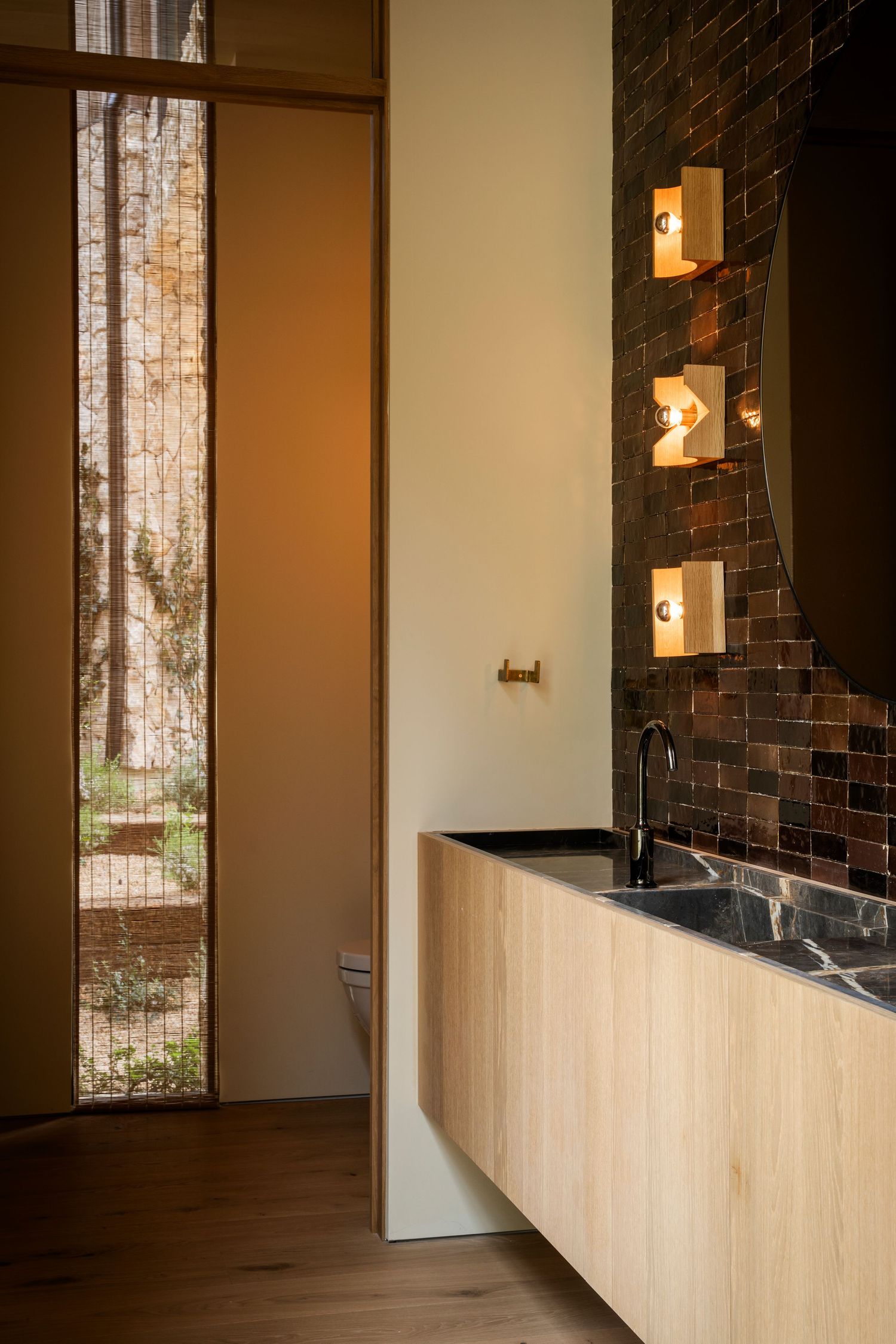 Modern interior hallway with exposed brick wall, light wood paneling, and wall-mounted sconce lighting fixtures.