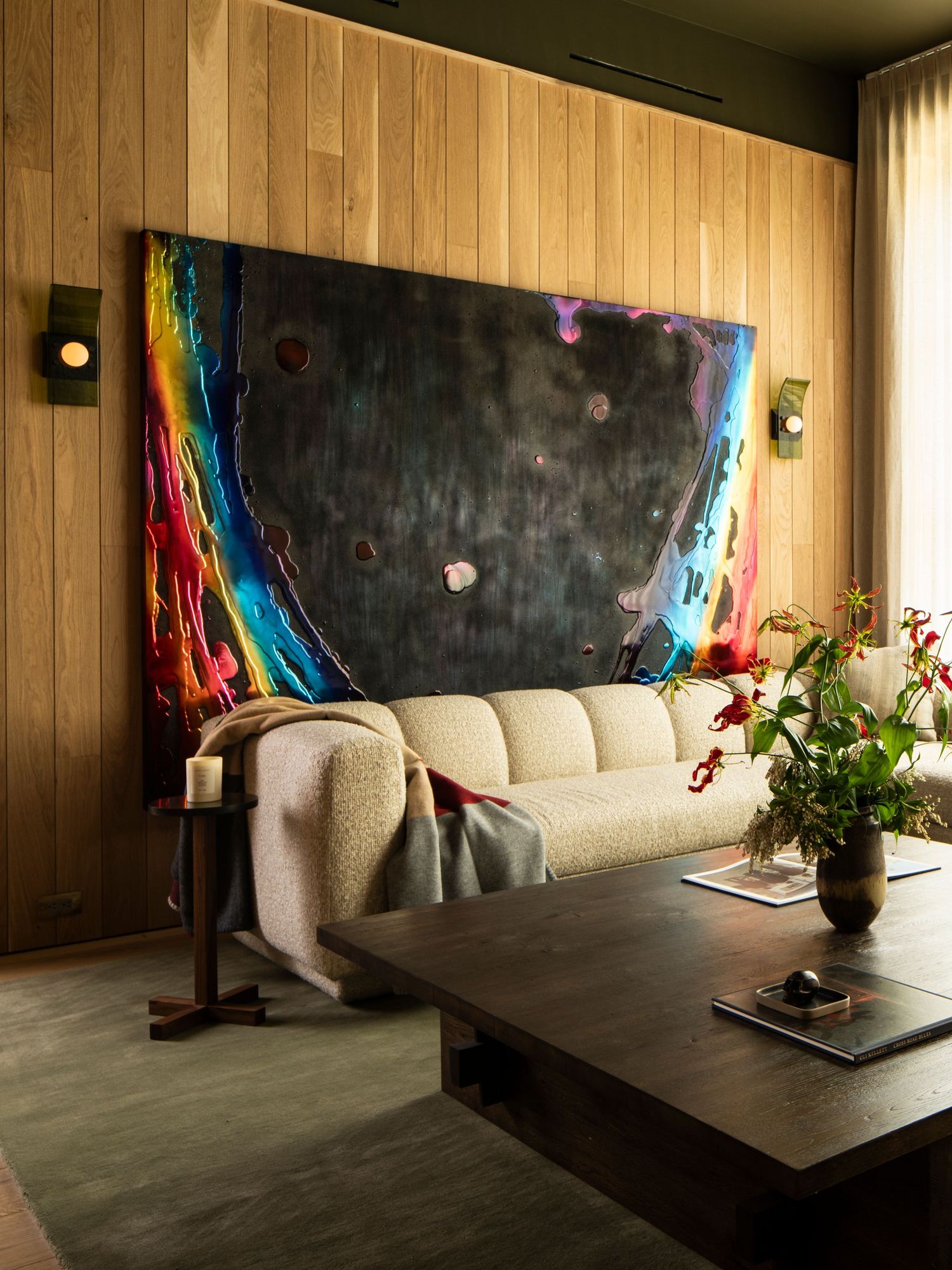 Modern living room with wood paneling, white sofa, dark coffee table, and colorful wall art in a series of five views.