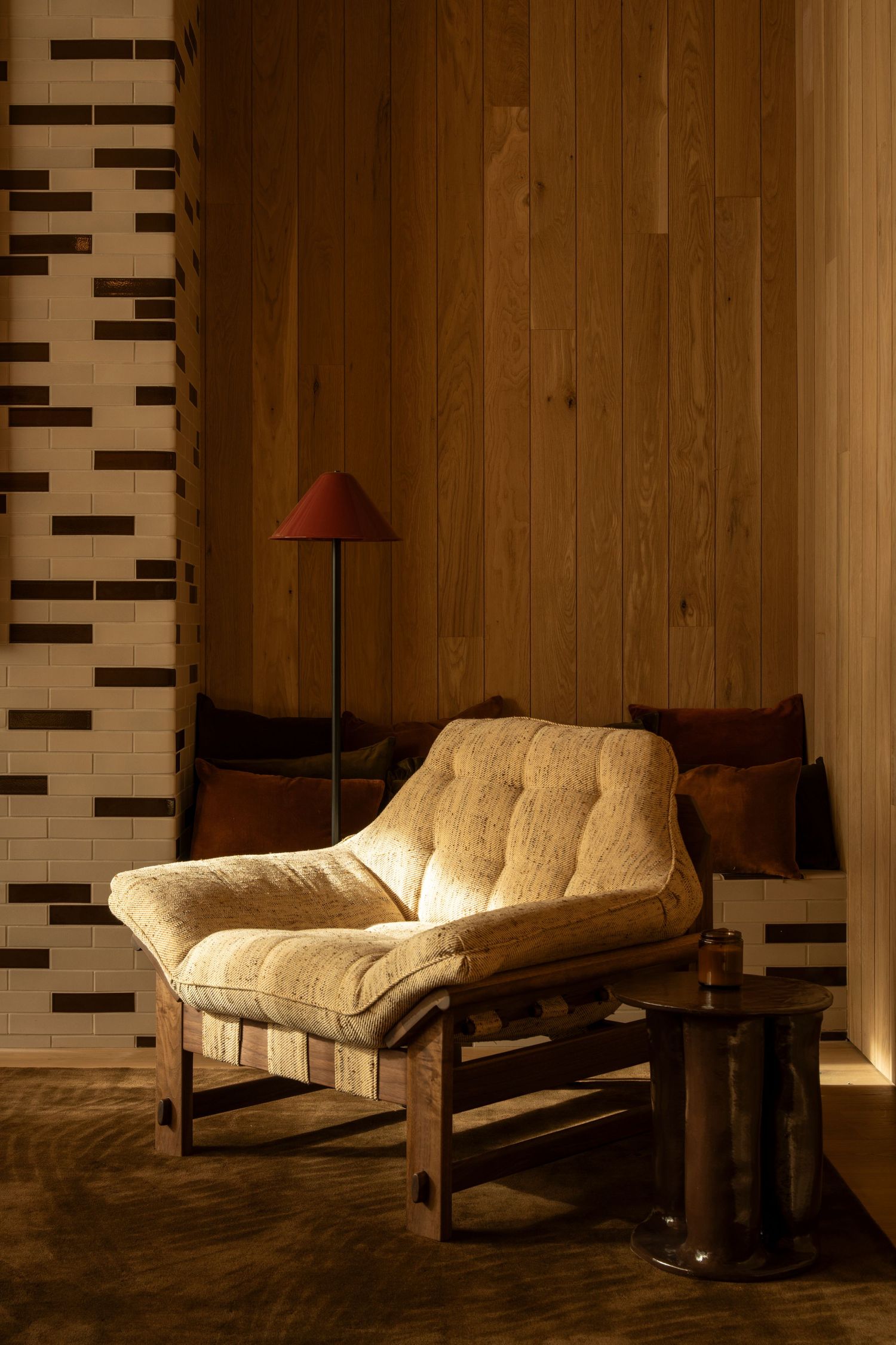 A sequence of photos showing a couch with white cushions and dark frame in warm lighting against a wooden wall.