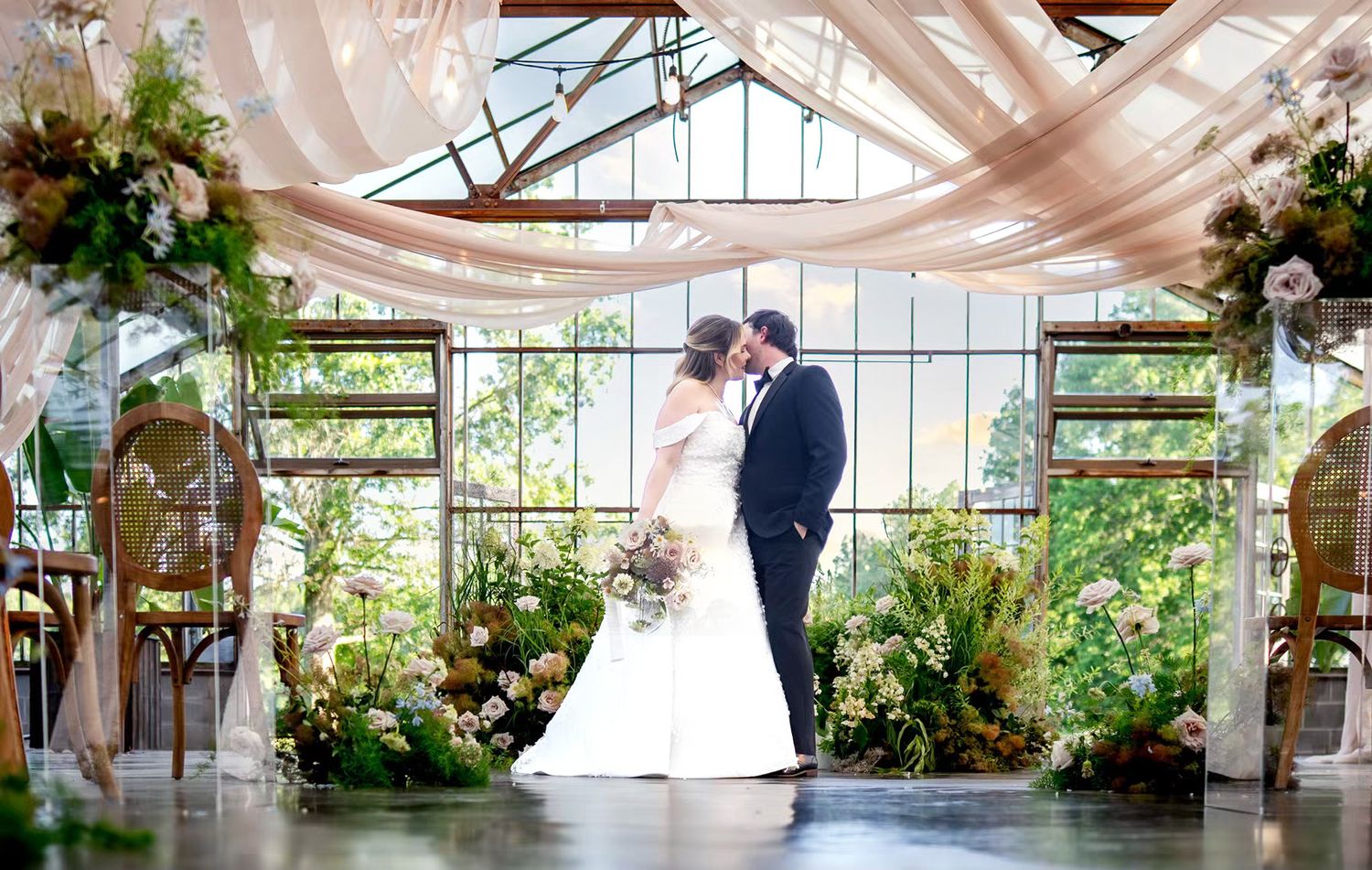 Bride and groom share a kiss in elegant greenhouse wedding venue in columbus ohio
