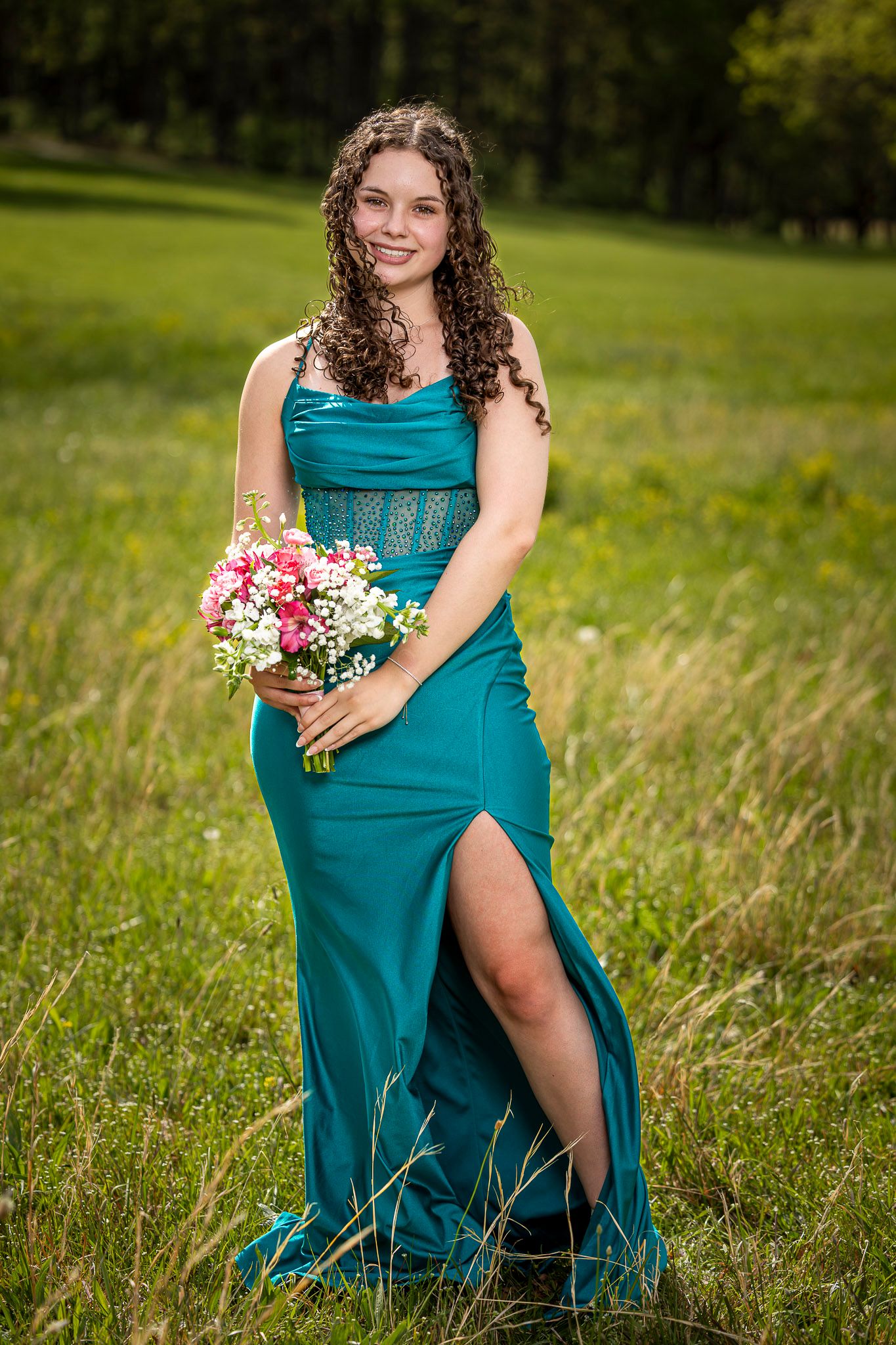 Young woman in teal gown holding pink bouquet smiling at Prairie Grove Battlefield