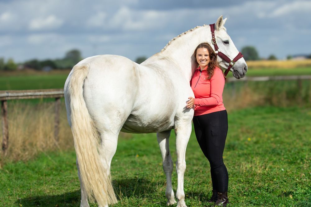 wit paard in het gras met meisje