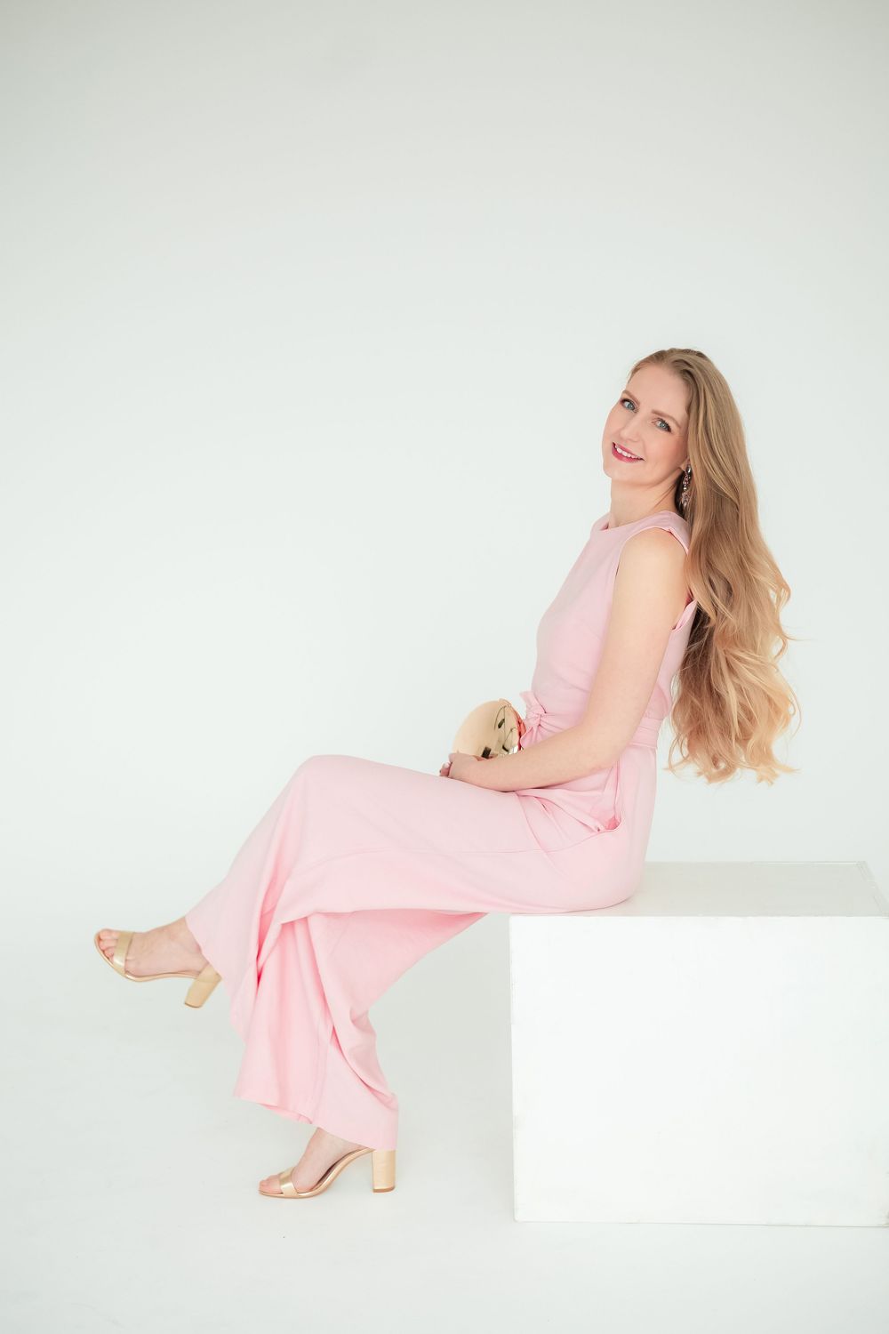 Ateliérový portrét ženy v ružovom bezrukávovom overale pózujúcej v minimalistickom štúdiu. Portrétny fotograf, Rajecká dolina.